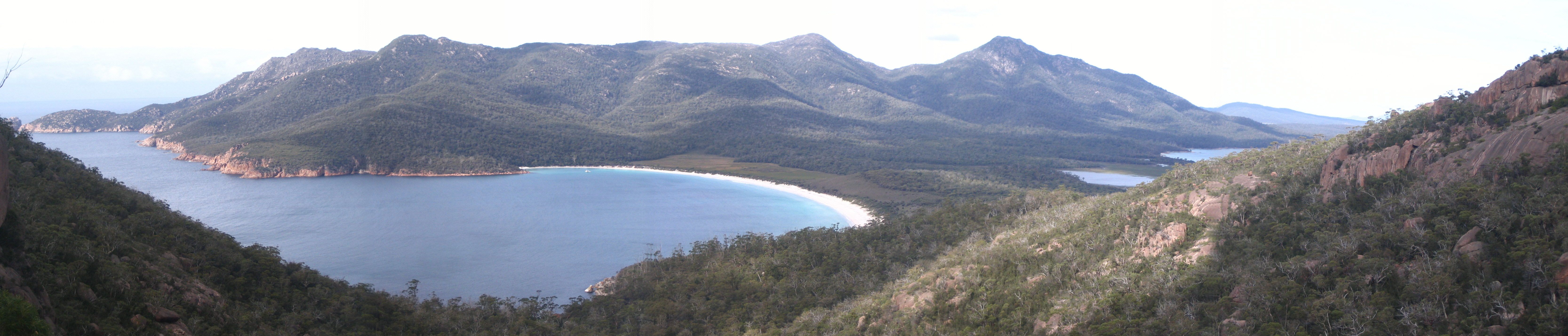 Wineglass Bay is the secluded bay in the centre of this photo, taken from a lookout point above it to the west. - rt) ot. de LW rt Ho A

 

fo oy LP
-

i 1 ar [

 

 

. ow i] Ls
elle |
: x 3
3 : = -
8 ;
\., r
| {
