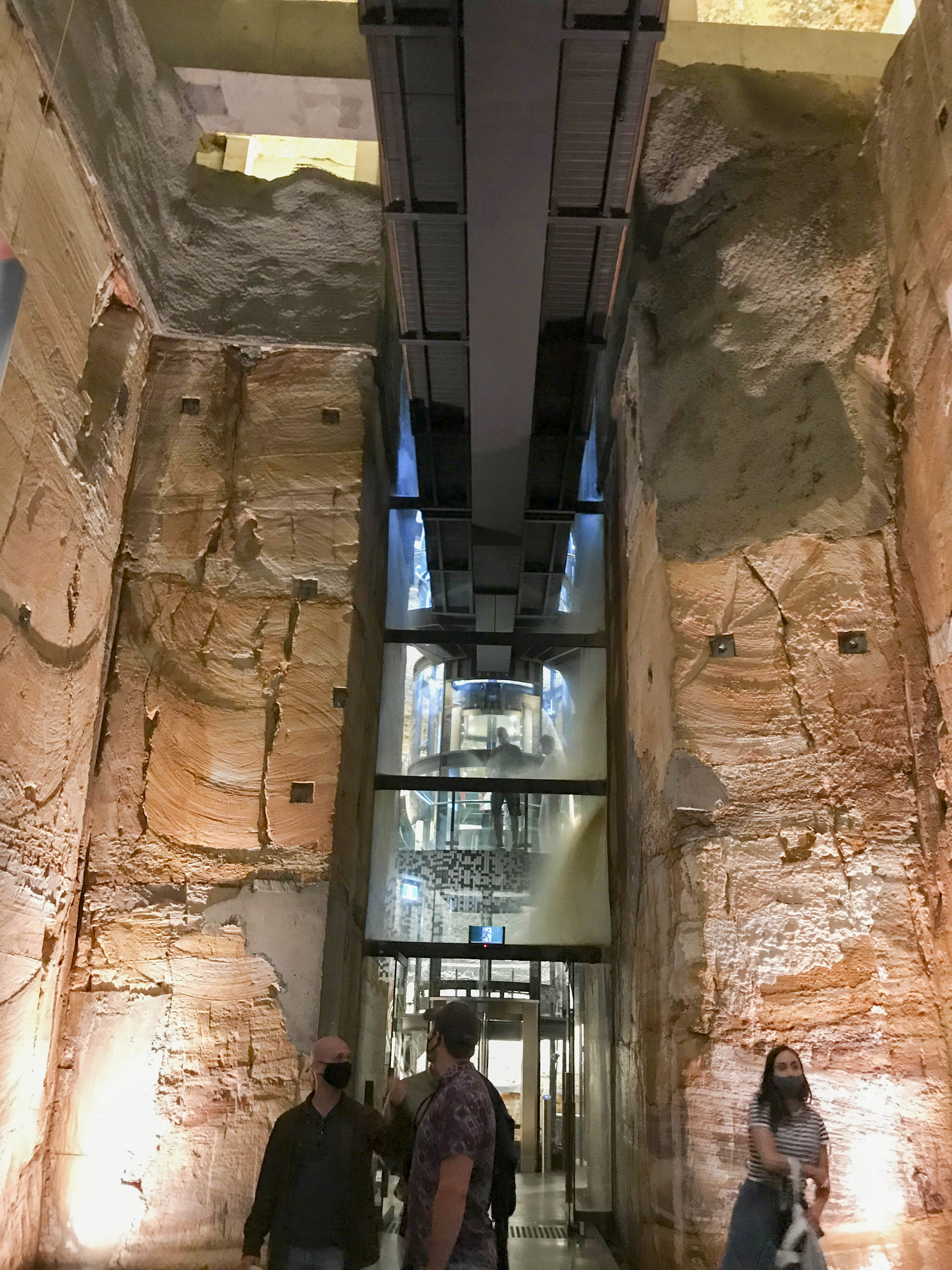 Looking back towards the glass elevator and spiral staircase from the lowest floor.  The outer end of the rock anchors can be seen on the rock face at various locations, typified by small square recesses featuring anchor bar, locking nut and square end plate
